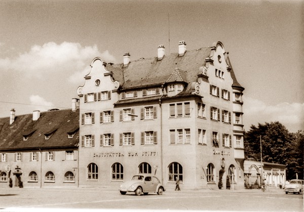 Ein historisches Gebäude mit geschwungenen Giebeln steht neben einem alten Auto.
