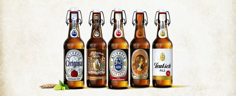 Fünf verschiedene Bierflaschen stehen nebeneinander auf einem hellen Untergrund.