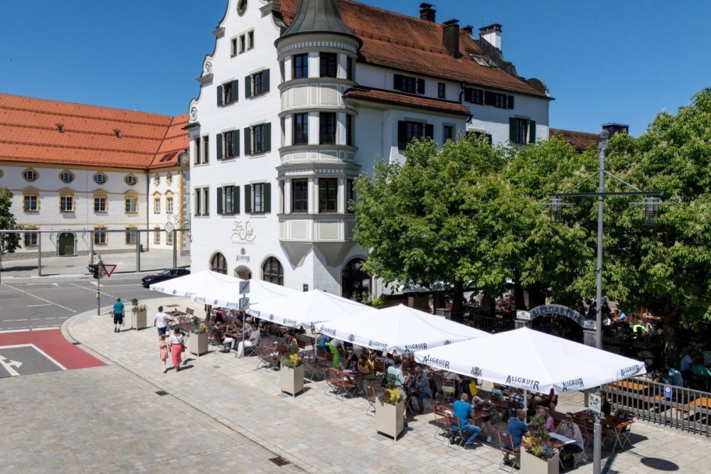 Aussenansicht der Gastätte Zum Stift in Kempten, im Vordergrund Allgäuer Brauhaus Schirme, dahinter ein Biergarten.