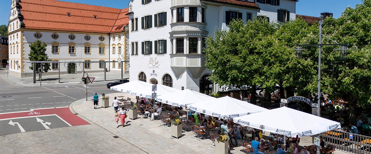 Aussenansicht der Gastätte Zum Stift in Kempten, im Vordergrund Allgäuer Brauhaus Schirme, dahinter ein Biergarten.