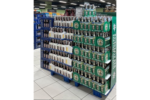 Eine Auslage verschiedener Bierflaschen in einem Supermarkt ist aufgereiht.